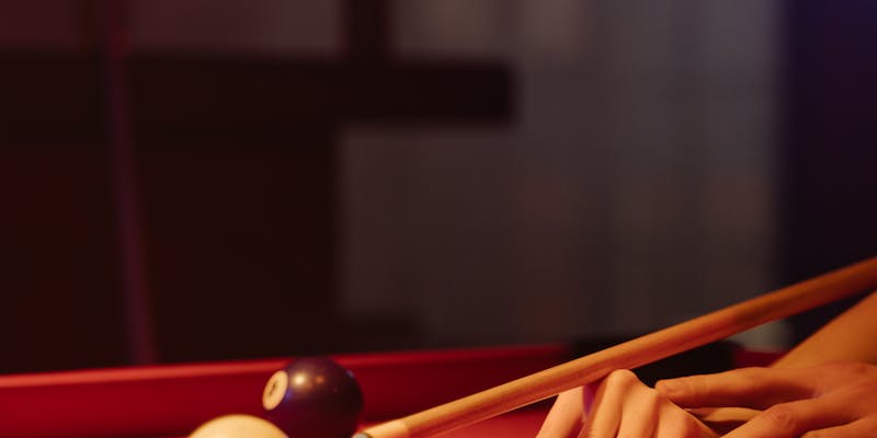 Close-up of cue ball and cue stick on pool table in moody lighting
