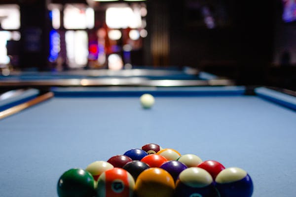 Racked pool balls on blue felt table in a dimly lit billiards venue